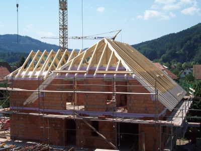 Dachstuhl aus Holz auf dem Rohbau, im Hintergrund die bewaldeten Hügel des Kinzigtals